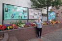 Natalie next to the boards in Whitehaven which features many of her paintings